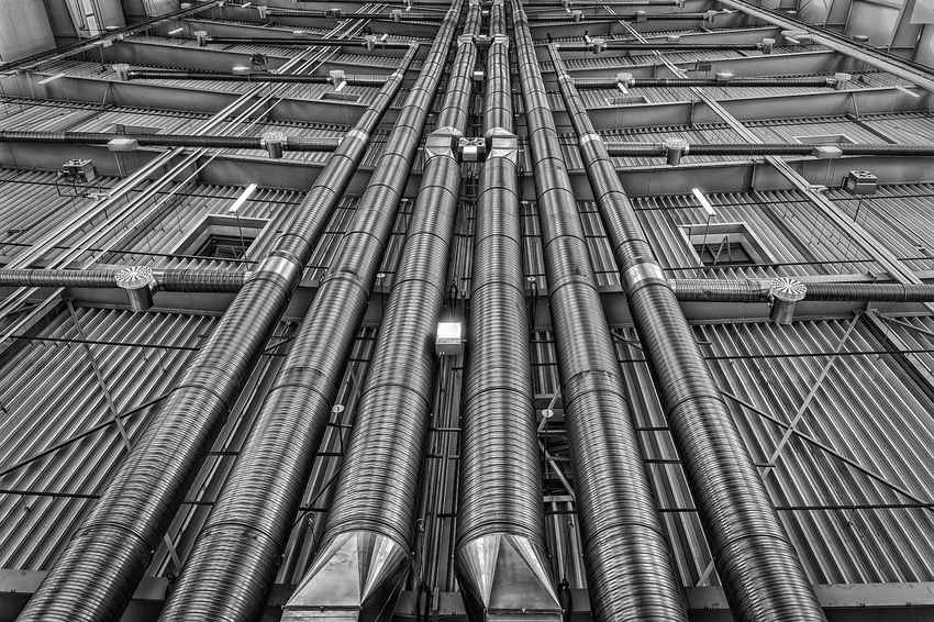 Conduit métallique vertical traversant un plafond avec grille de ventilation Conduit métallique vertical traversant un plafond avec grille de ventilation