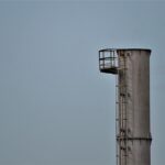 Une haute cheminée avec plateforme et échelle contre un ciel gris