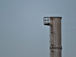 Une haute cheminée avec plateforme et échelle contre un ciel gris
