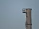 Une haute cheminée avec plateforme et échelle contre un ciel gris
